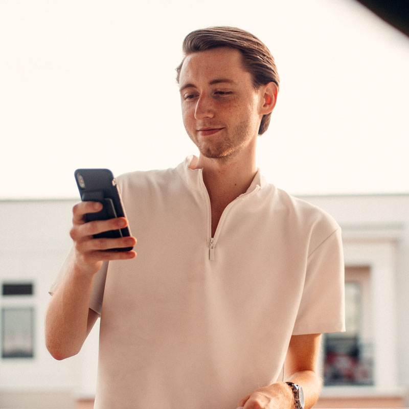 A man in a white t-shirt looking at his phone